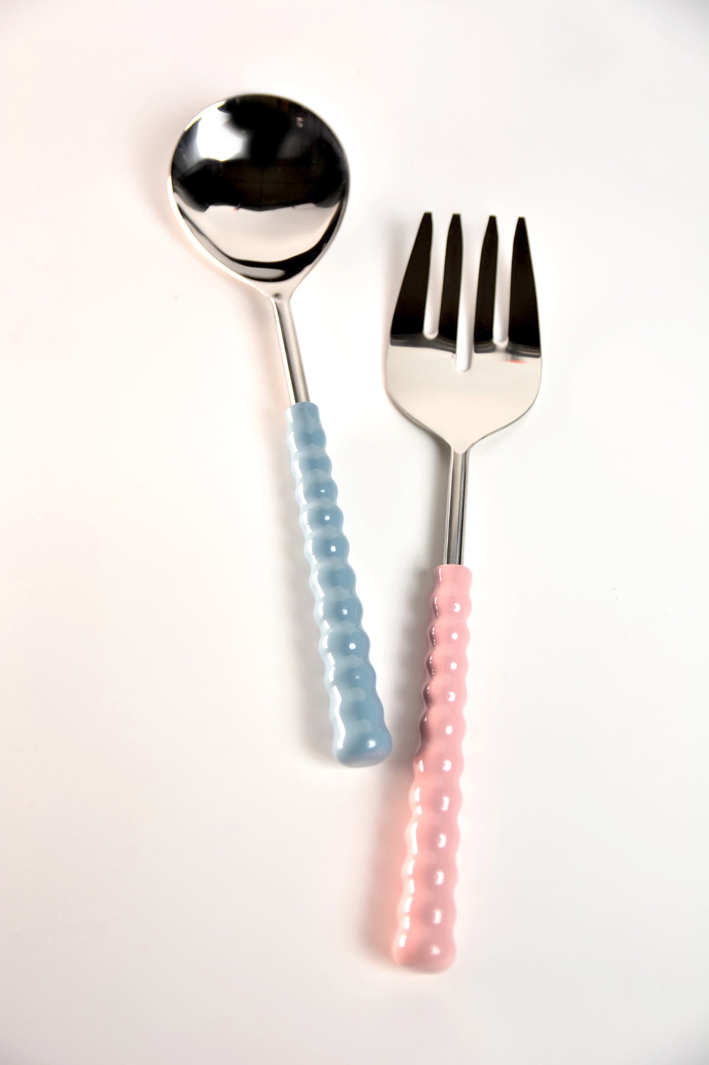 Spoon and fork with pastel blue and pink handles on a white background