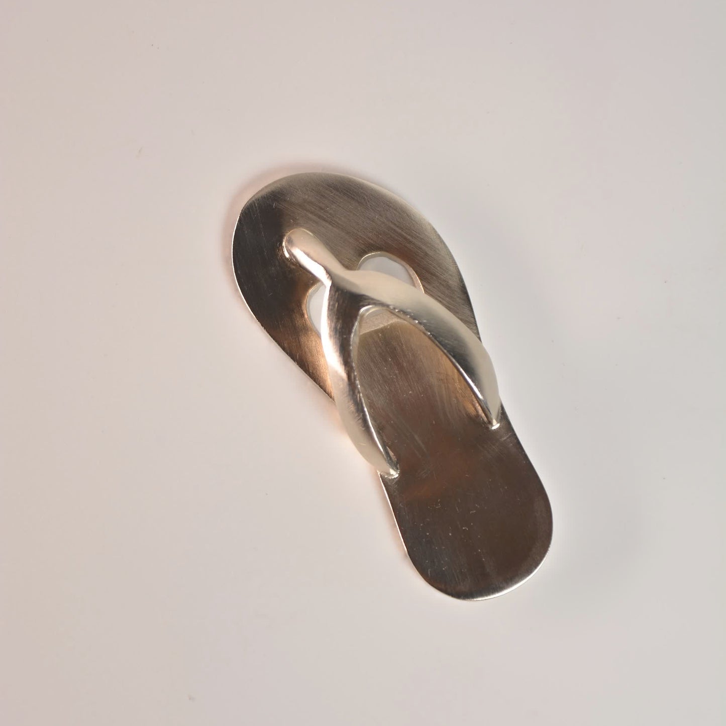 Metallic flip-flop sandal on a light gray background