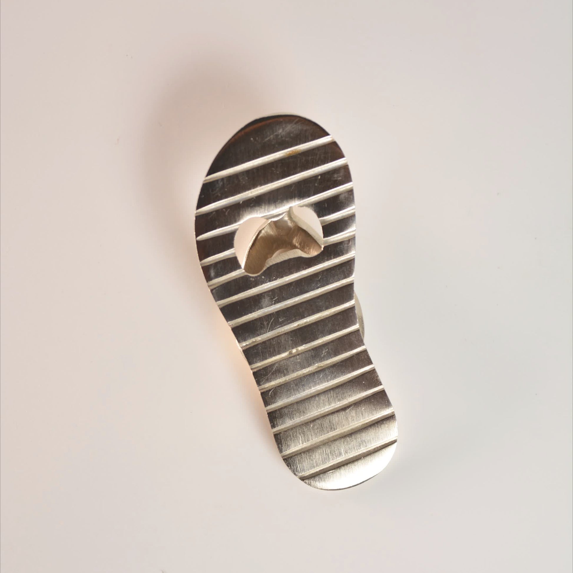 Metallic sandal-shaped object on a light background