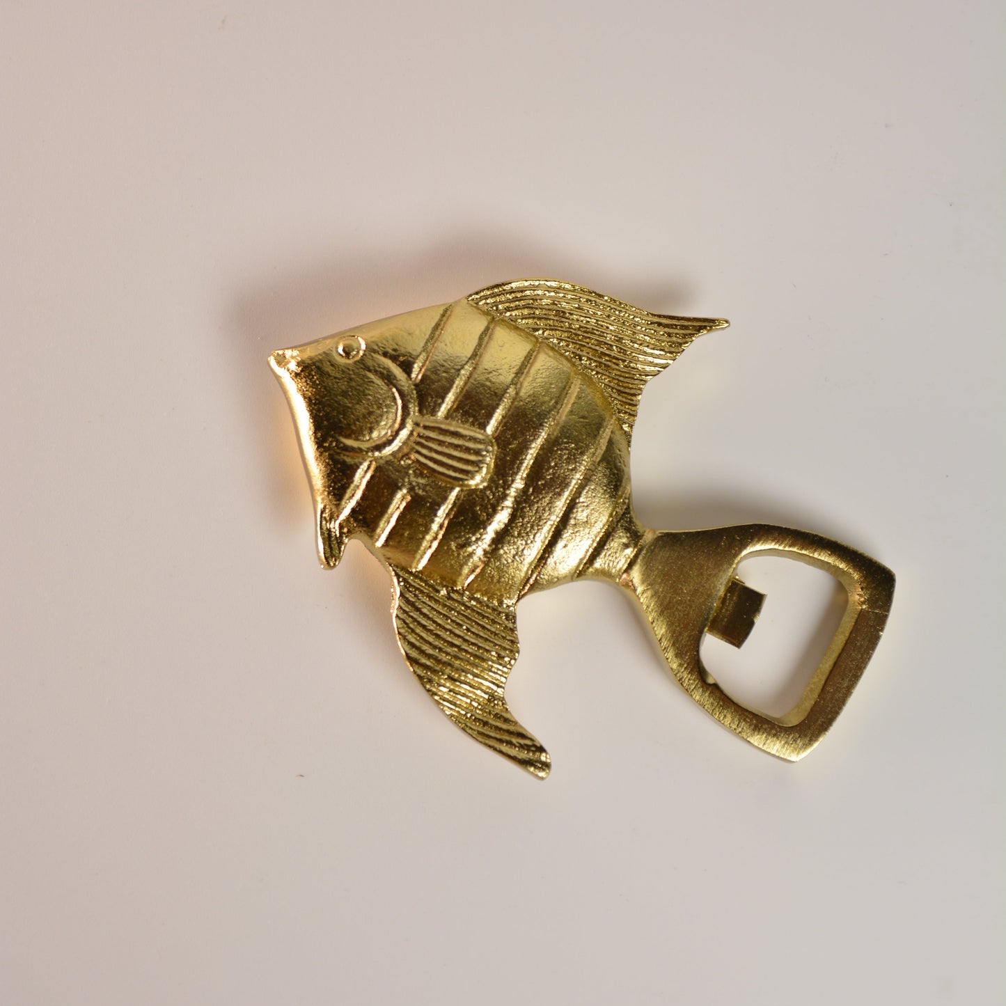 Gold fish-shaped bottle opener on a white background